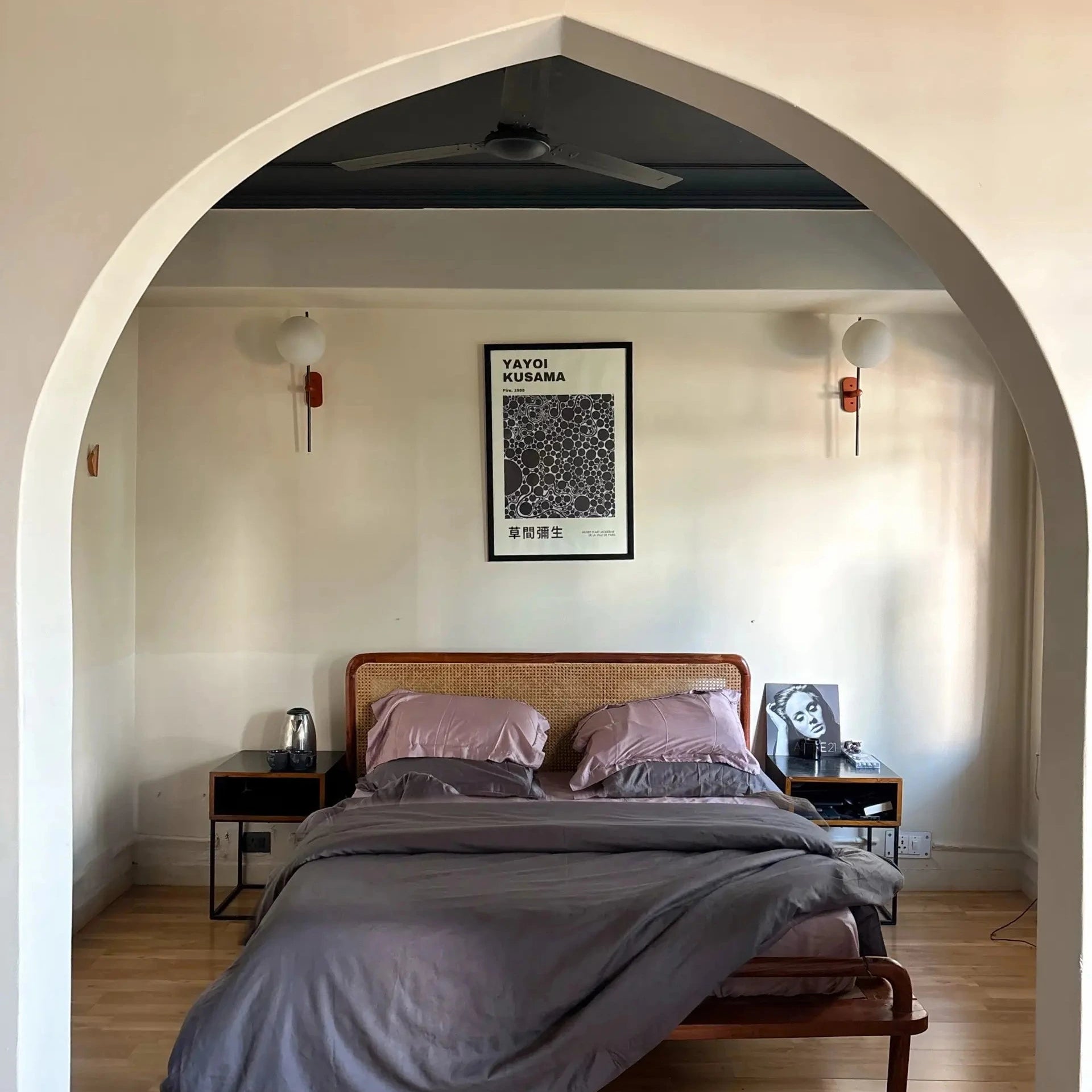 Bedroom with wooden bed, gray bedding, and framed artwork on the wall.