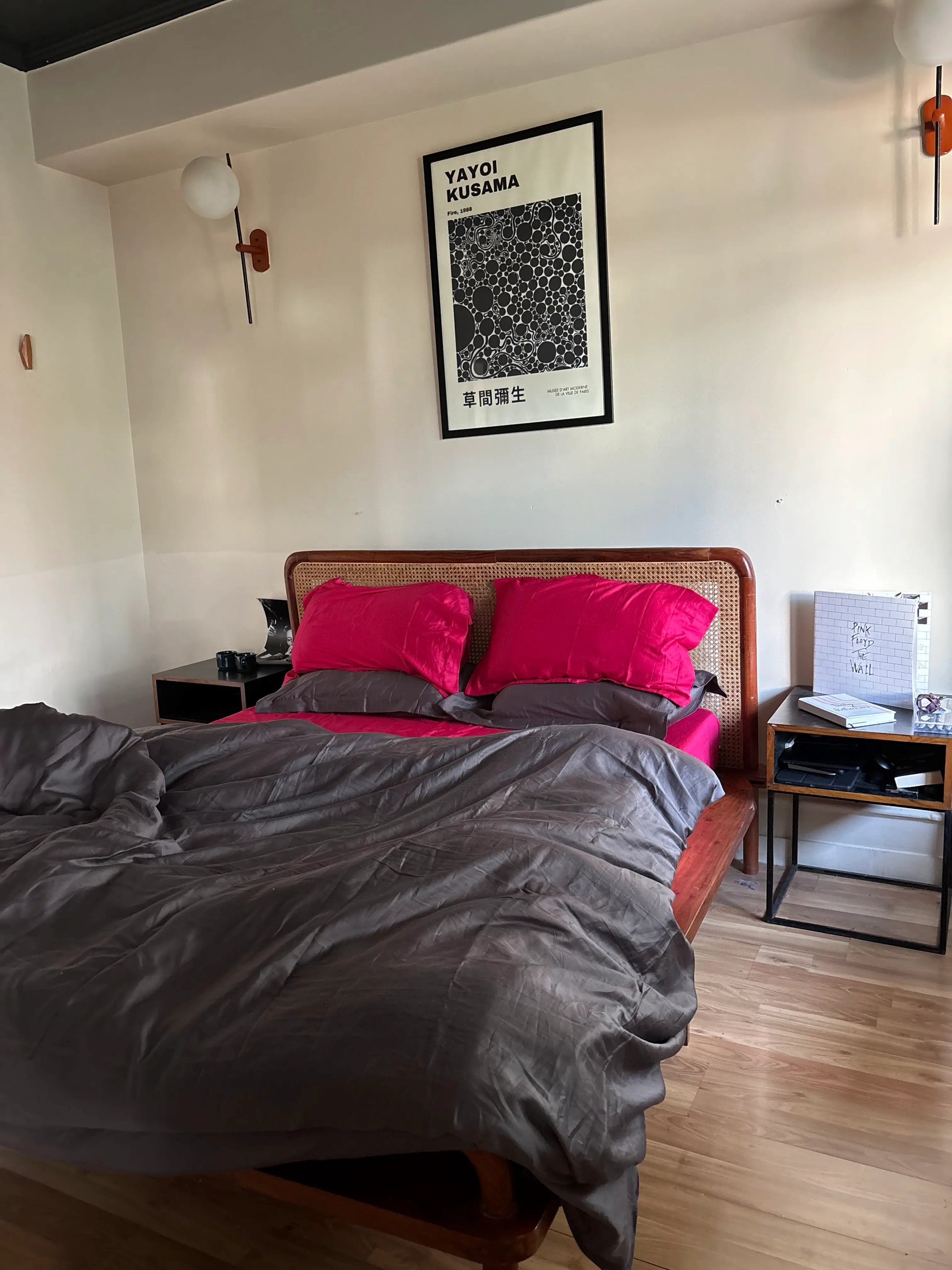 Bedroom with a bed featuring pink pillows and gray bedding, framed artwork on the wall.