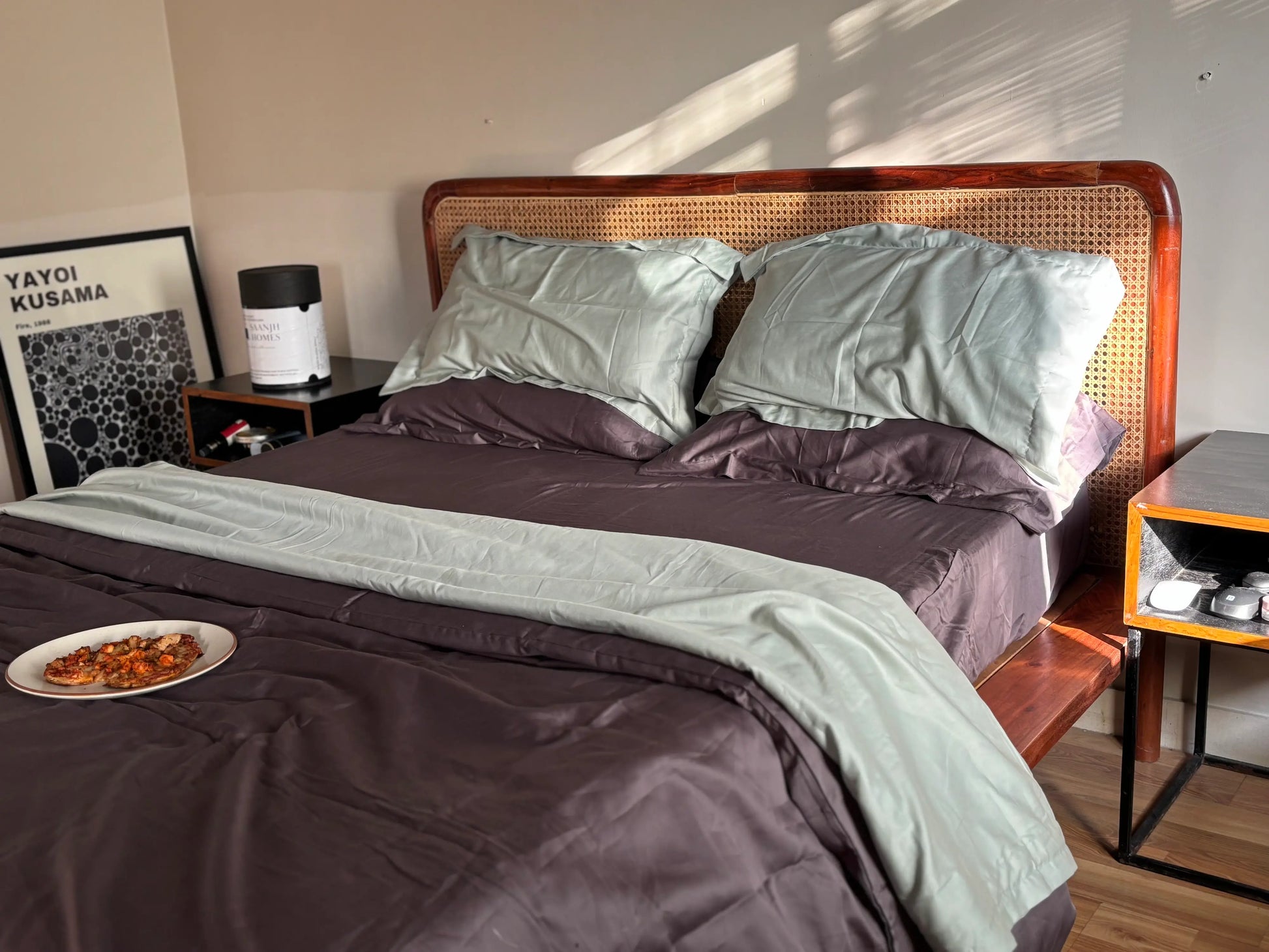 Bedroom with a bed featuring green and grey bedding, a nightstand, and a side table.