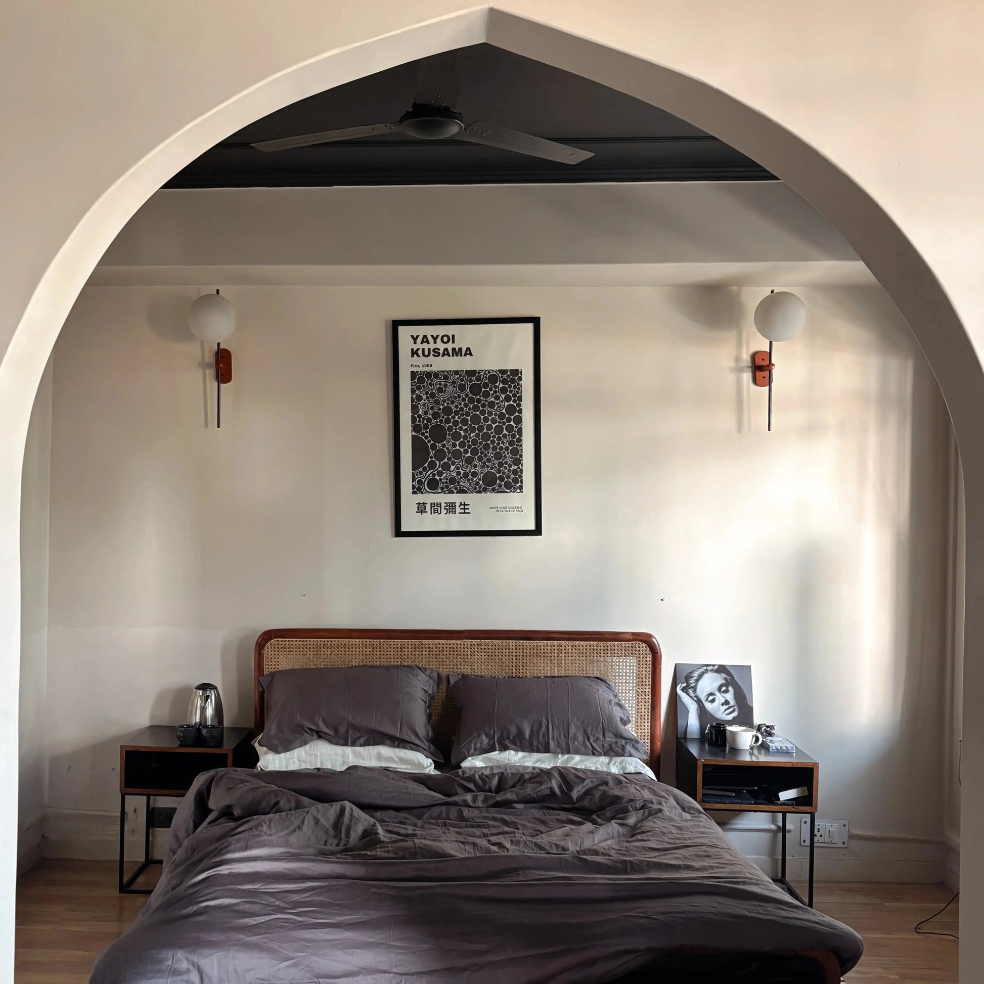 Bedroom with wooden bed, nightstands, and wall art framed by an archway.