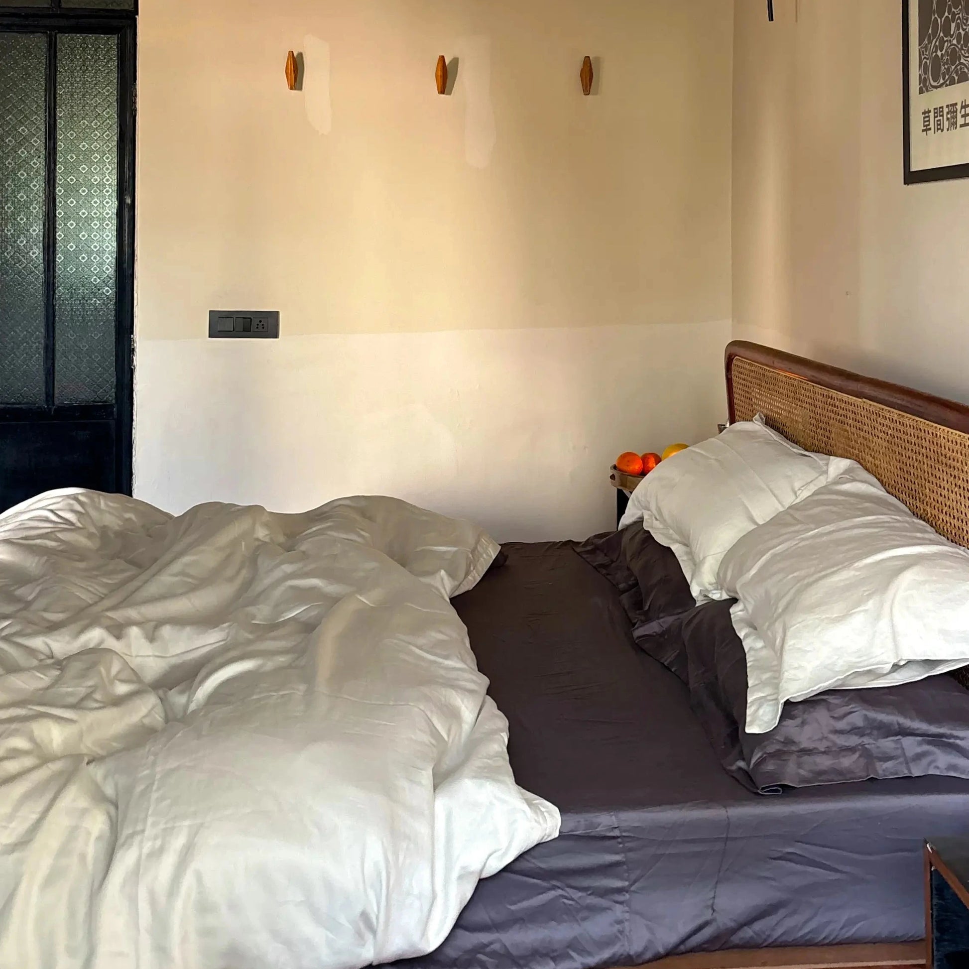 bed in a room with a ceiling fan and wall decorations. ash and creme bedding