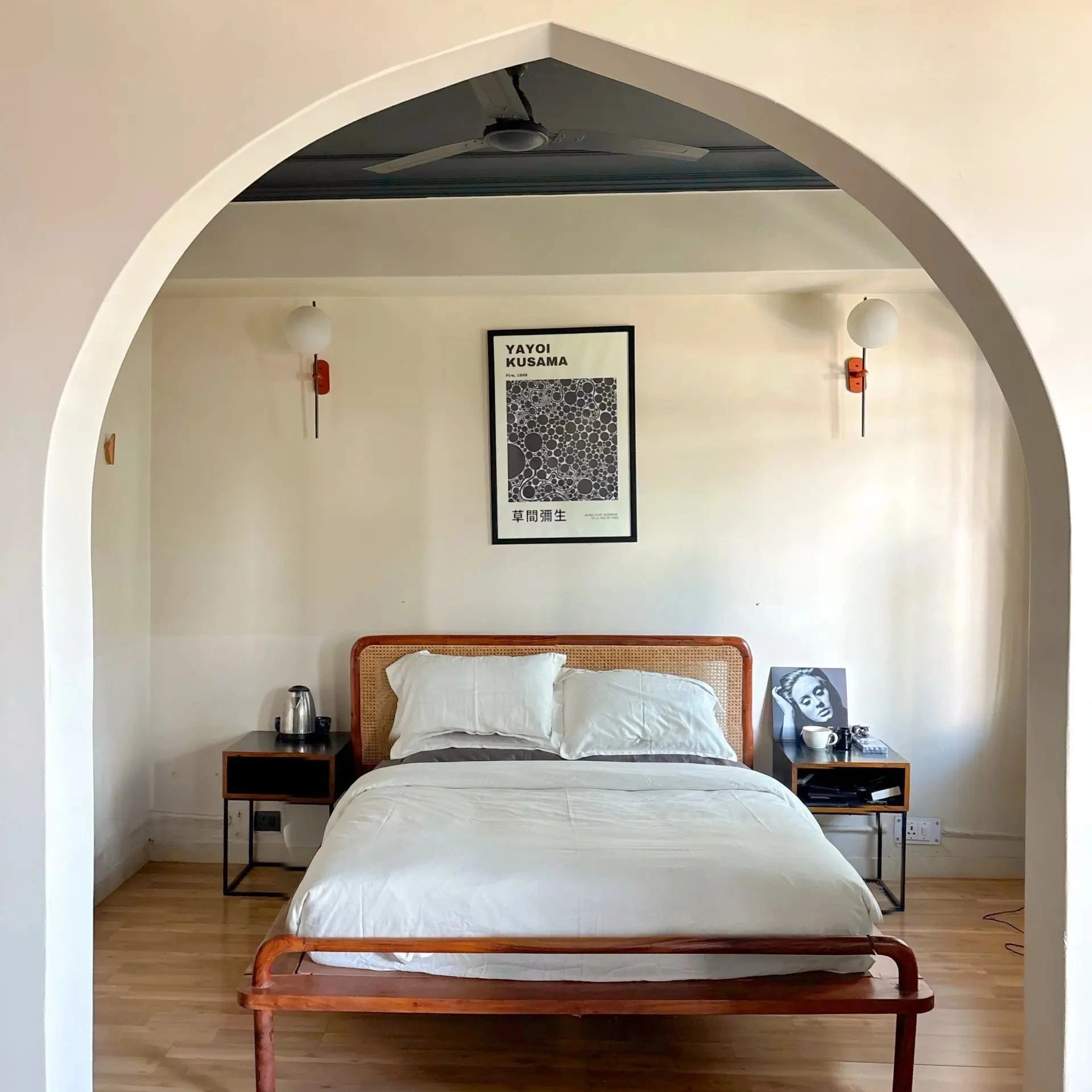 Bedroom with wooden bed and white bedding, framed artwork on the wall.