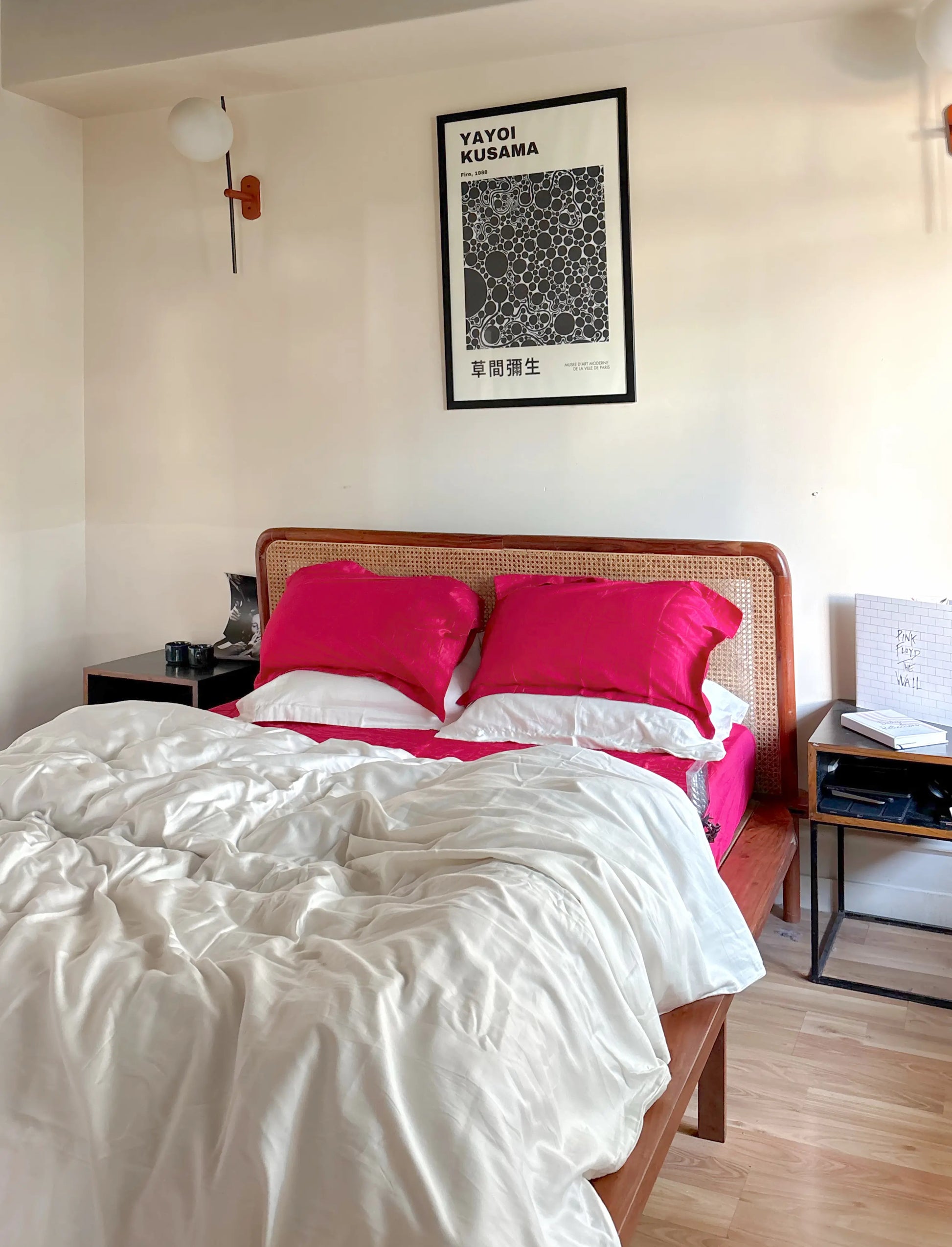 Bedroom with pink pillows on a bed, framed artwork on the wall, and nightstands.
