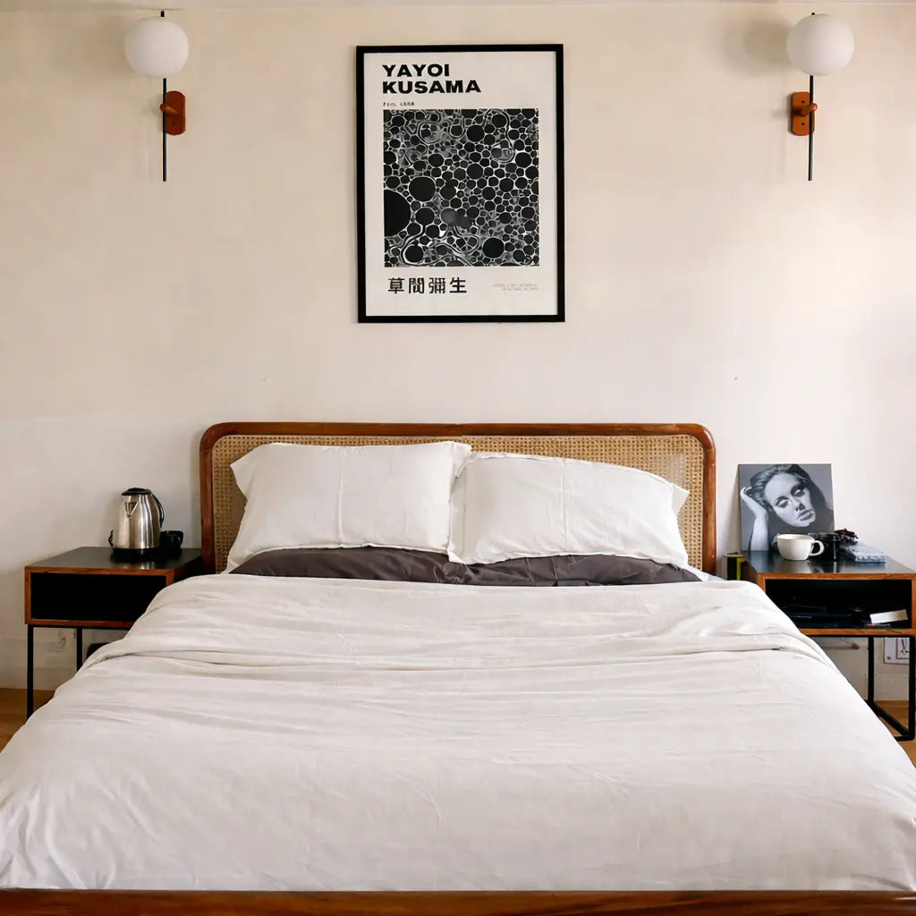 Bedroom with a bed, nightstands, and a framed Yayoi Kusama artwork on the wall.