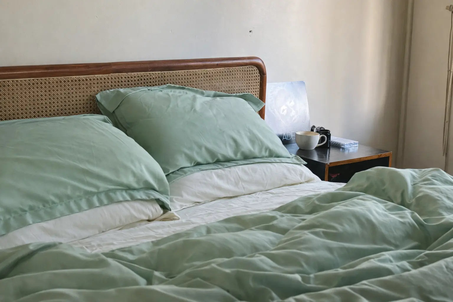 Bed with green bedding and pillows in a room setting. Cozy, Lux