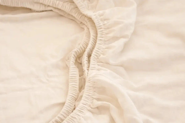 Close-up of a creme fitted sheet on a bed