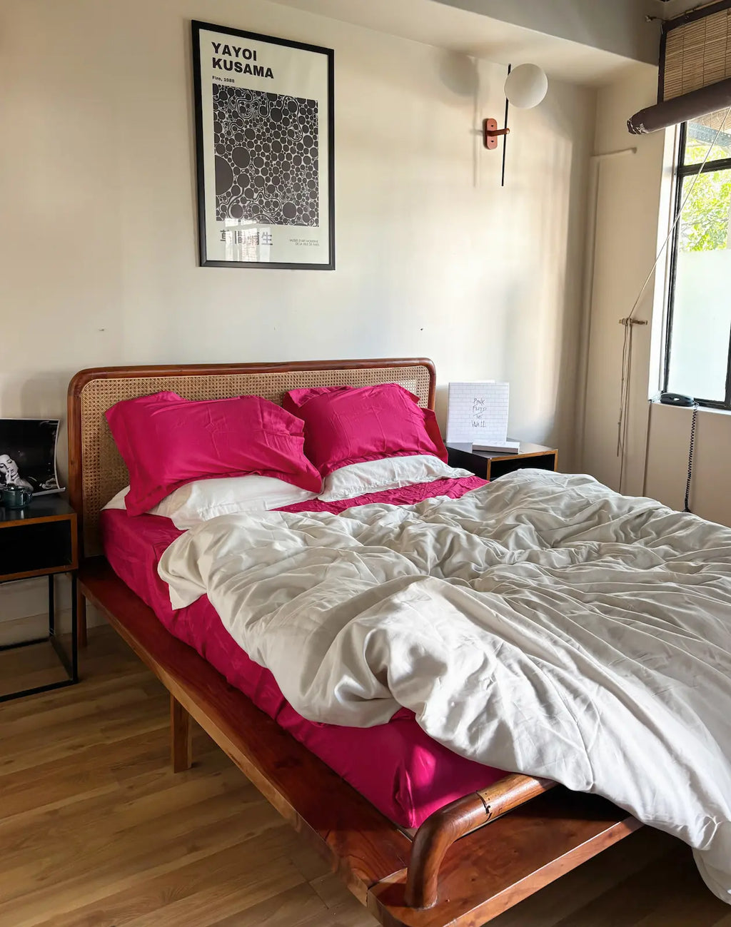 Bedroom with a bed featuring pink pillows and a white comforter, nightstands, and a framed picture on the wall. Saanjh Homes
