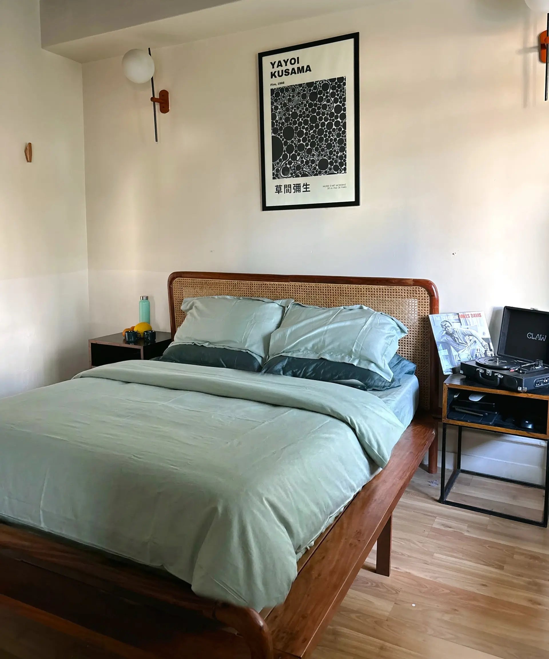 Bedroom with wooden bed, green bedding, and framed poster on wall.