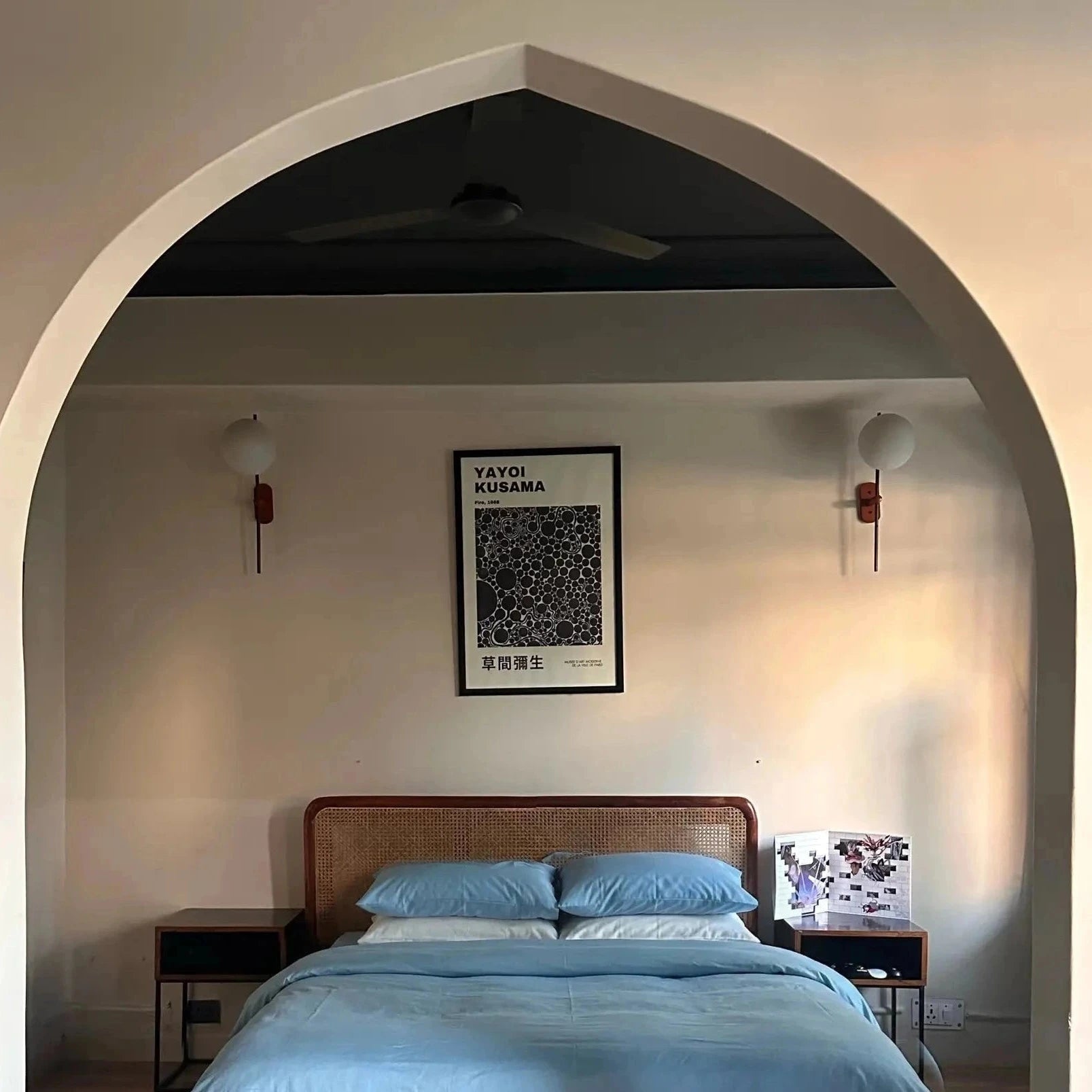 Bedroom with a bed, nightstands, and wall art framed by an archway.