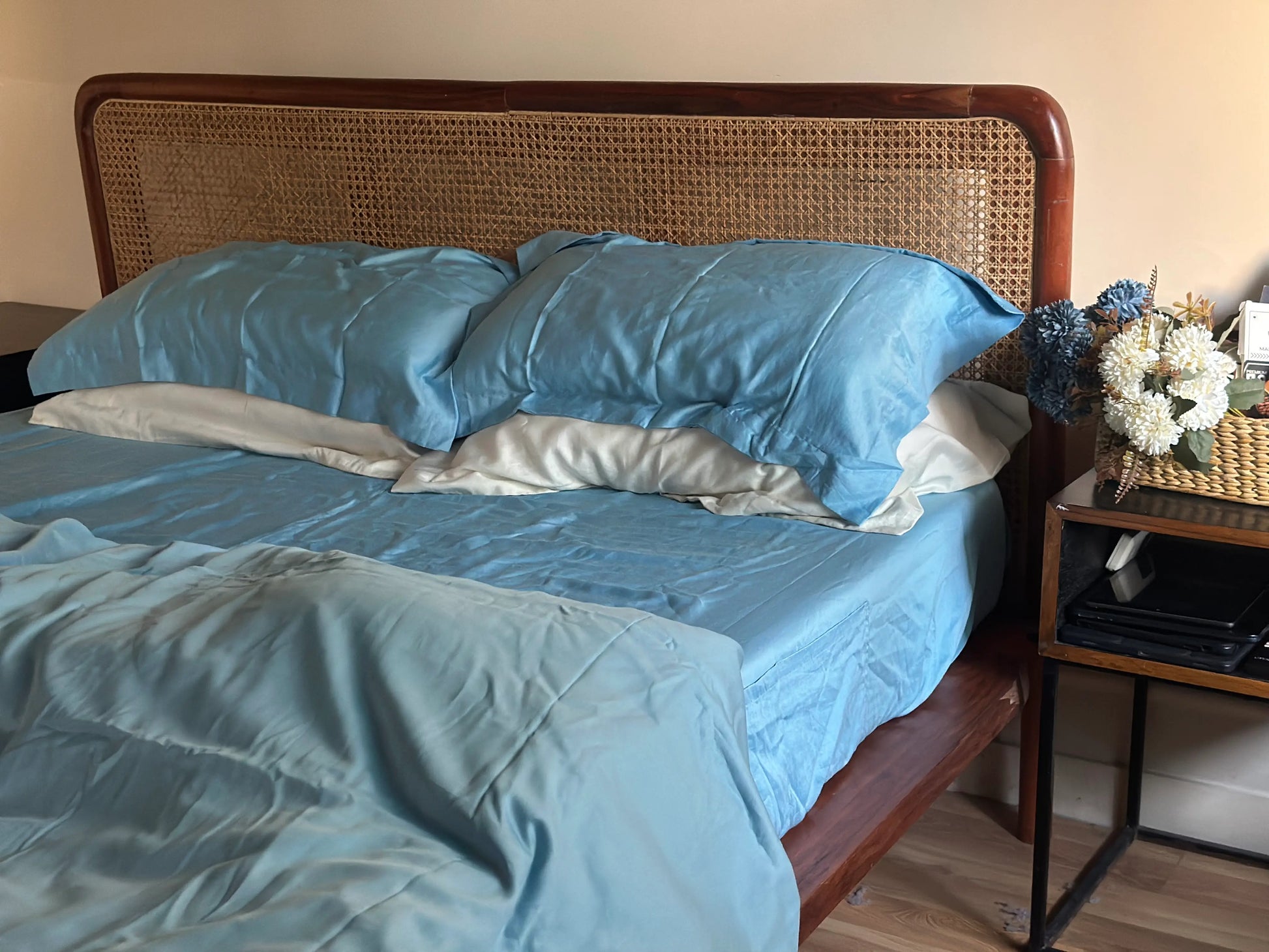 Bed with blue bedding and wicker headboard in a bedroom setting.