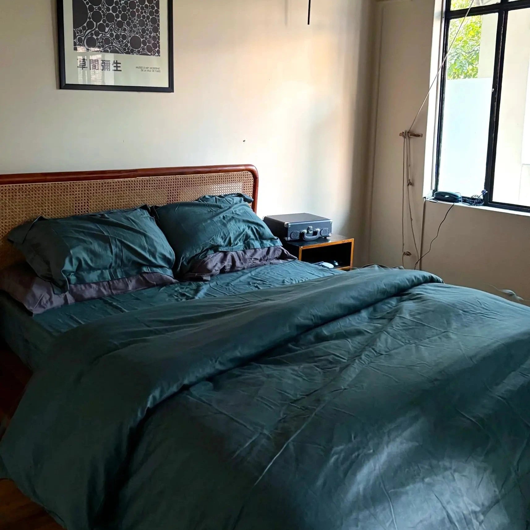 Bedroom with teal bedding, a framed picture on the wall, and a window.