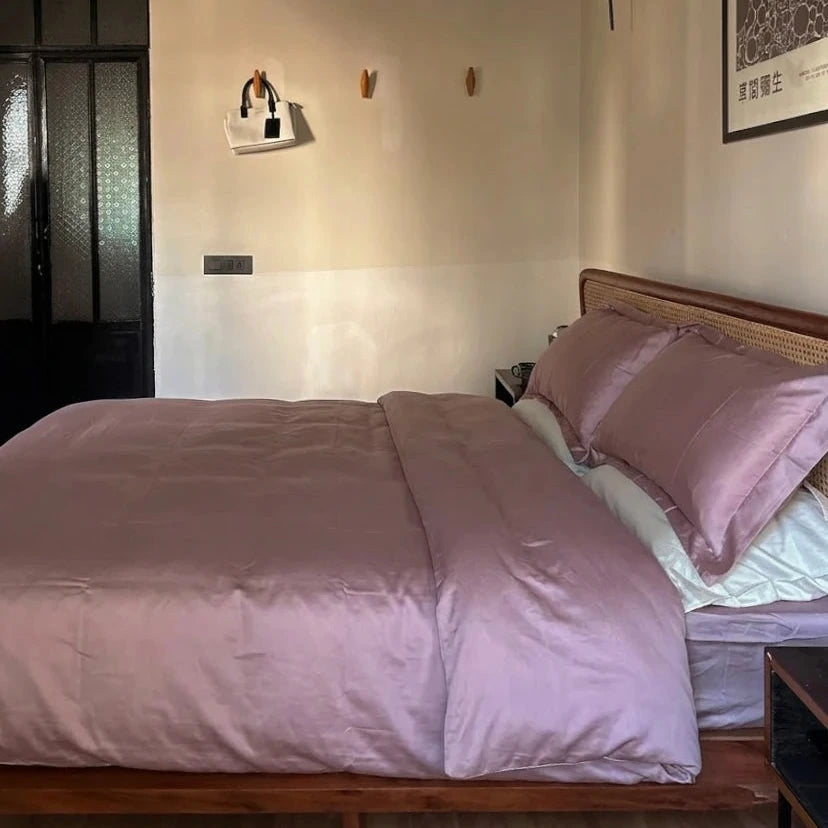 Bedroom with pink bedding and a framed picture on the wall.