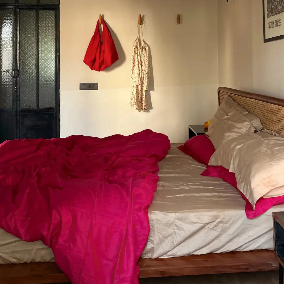 Bedroom with lingonberry blanket, toast bedsheet and red jacket hanging on the wall
